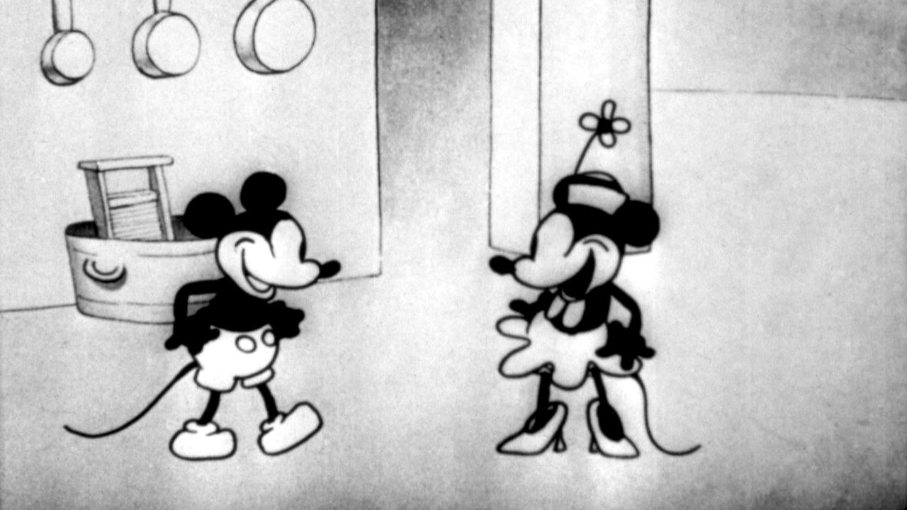 A still from public domain cartoon Steamboat Willie, featuring Mickey and Minnie Mouse smiling at each other on a steamboat.