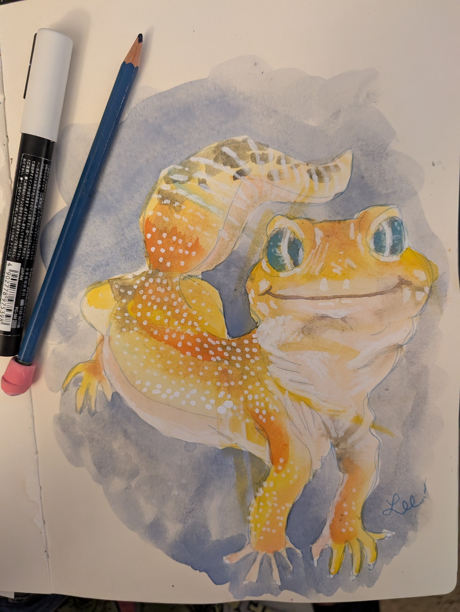 Watercolor of a smiling yellow-orange gecko with big blue eyes. A toddlers stray yellow paint lines can be seen around it's body.