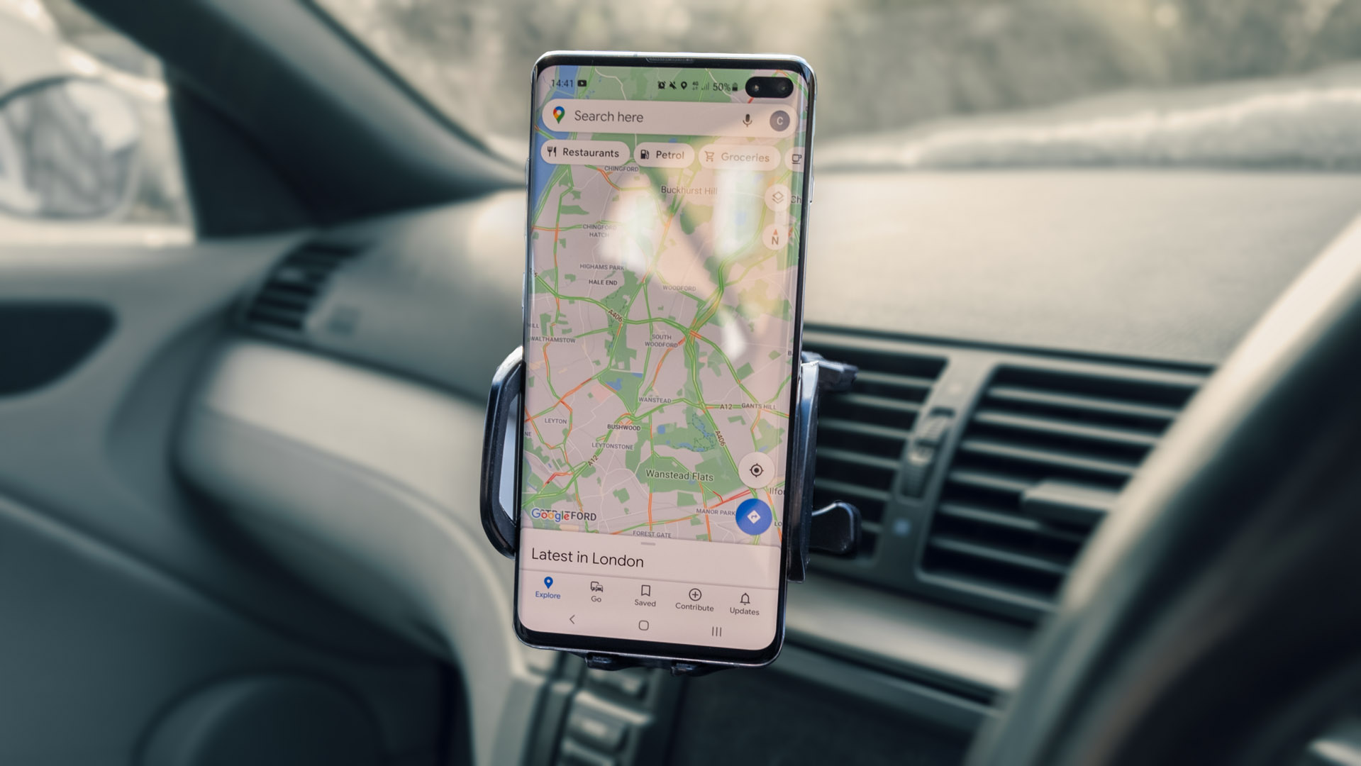 picture of a phone in a holder in a car, showing a maps app without a destination set yet.
