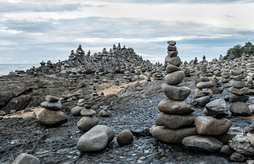 many piles of small stones on a rocky coastline