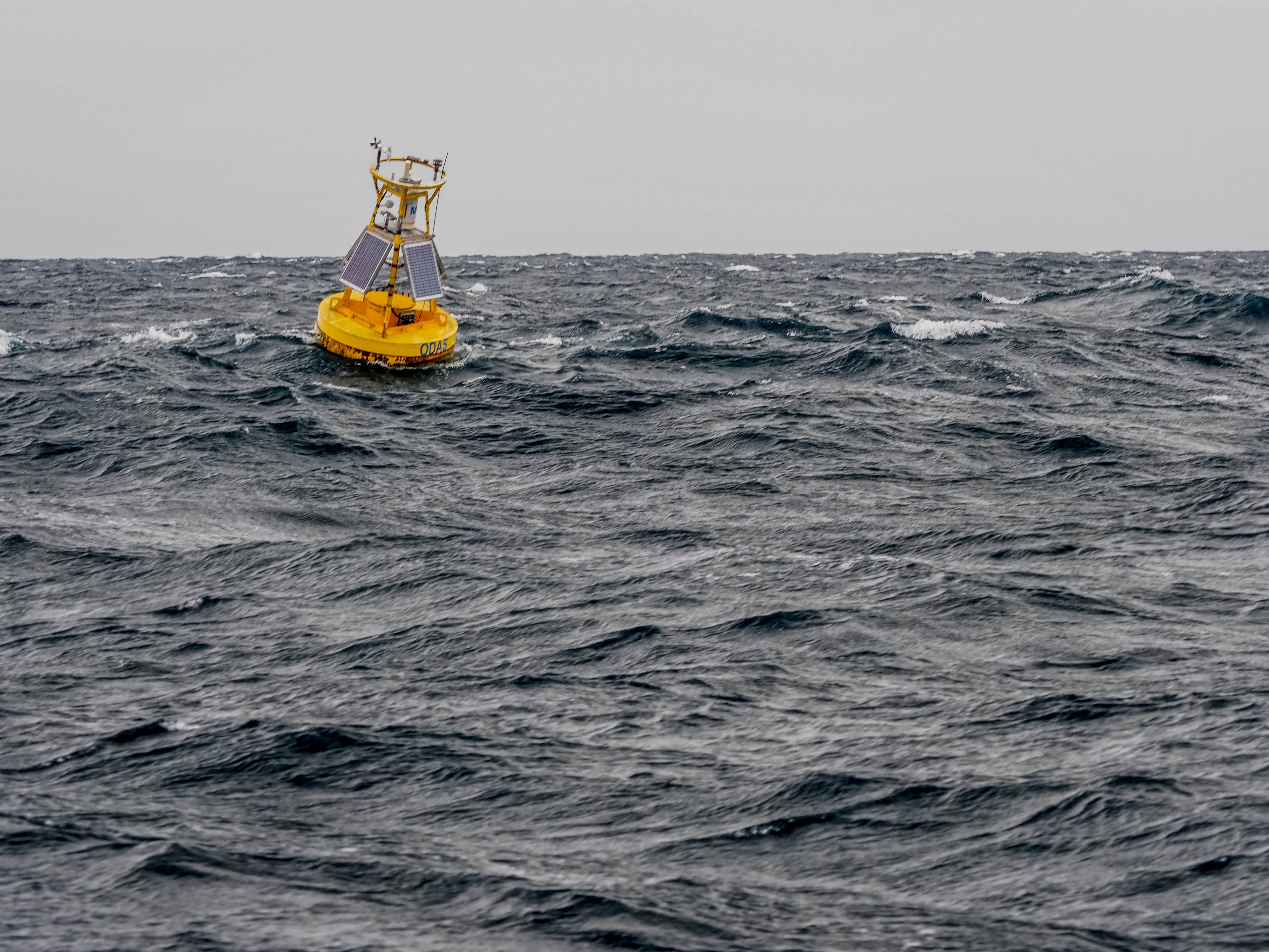 a yellow buoy floating in choppy water
