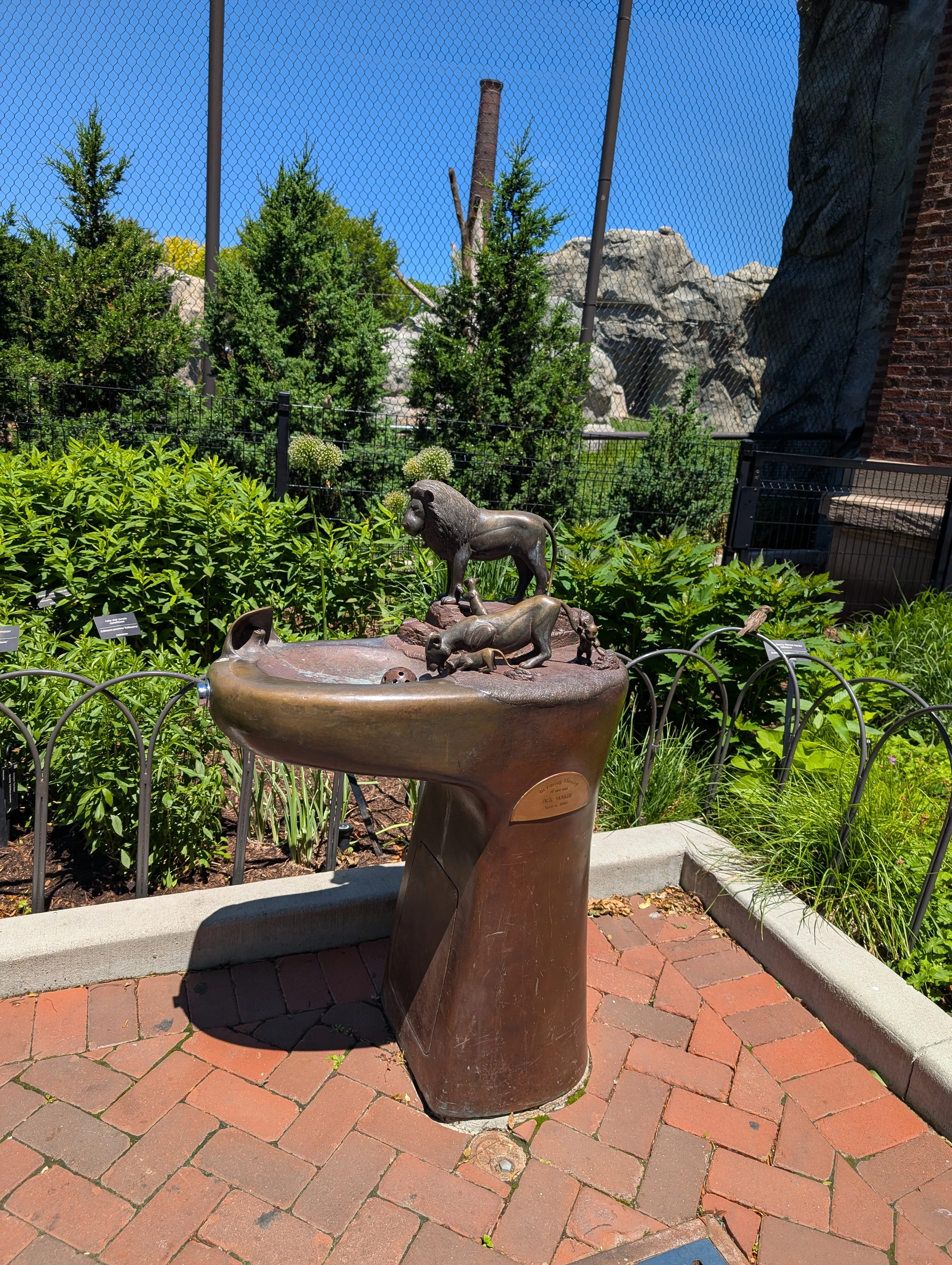 A water fountain with a lion family. The mom and baby are drinking water from the fountain bowl while the daddy lion keeps watch. Serious Lion King vibes going on here.