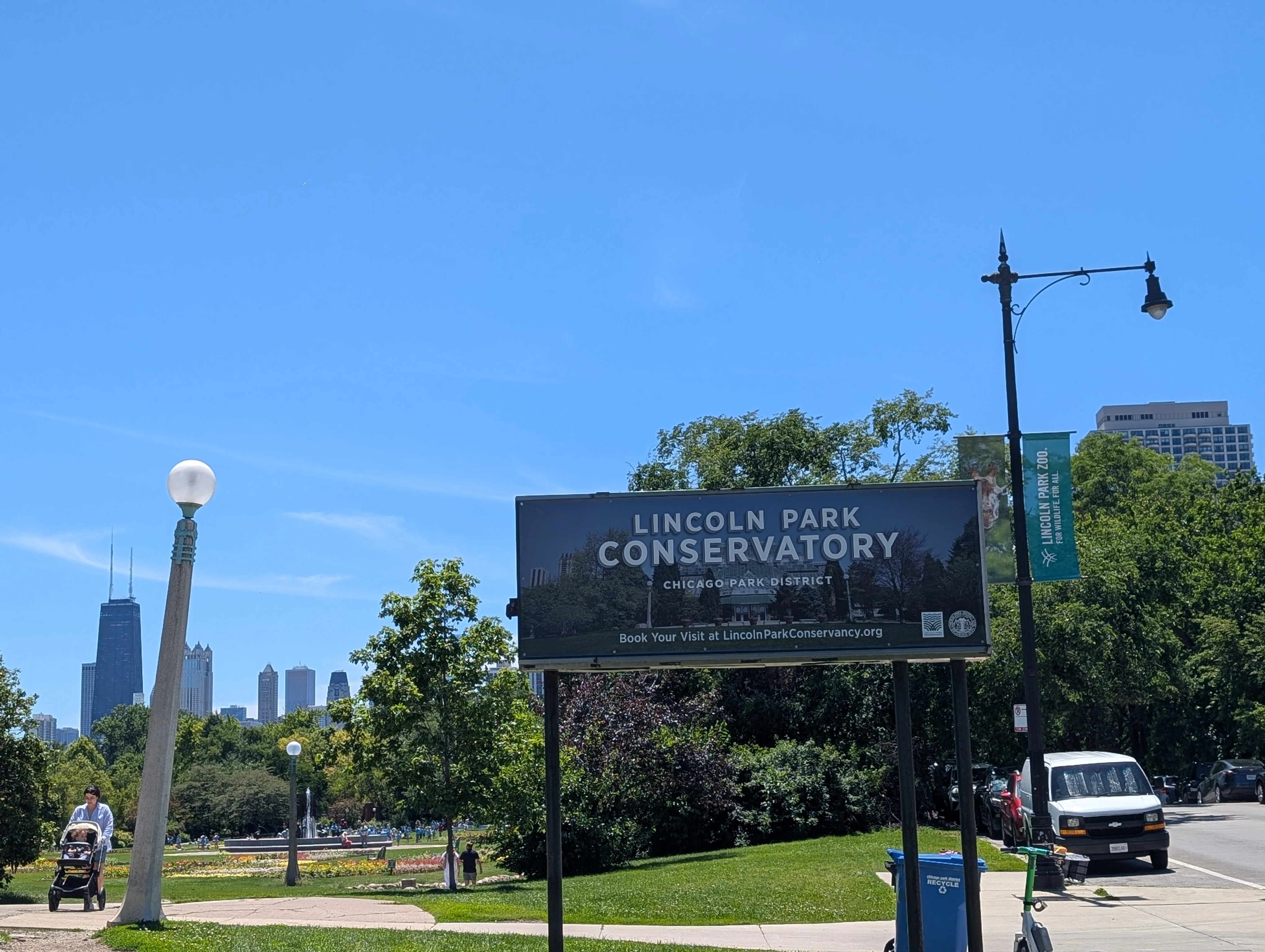 A photo of the Lincoln Park Conservatory sign with a partial Chicago skyline in the background.