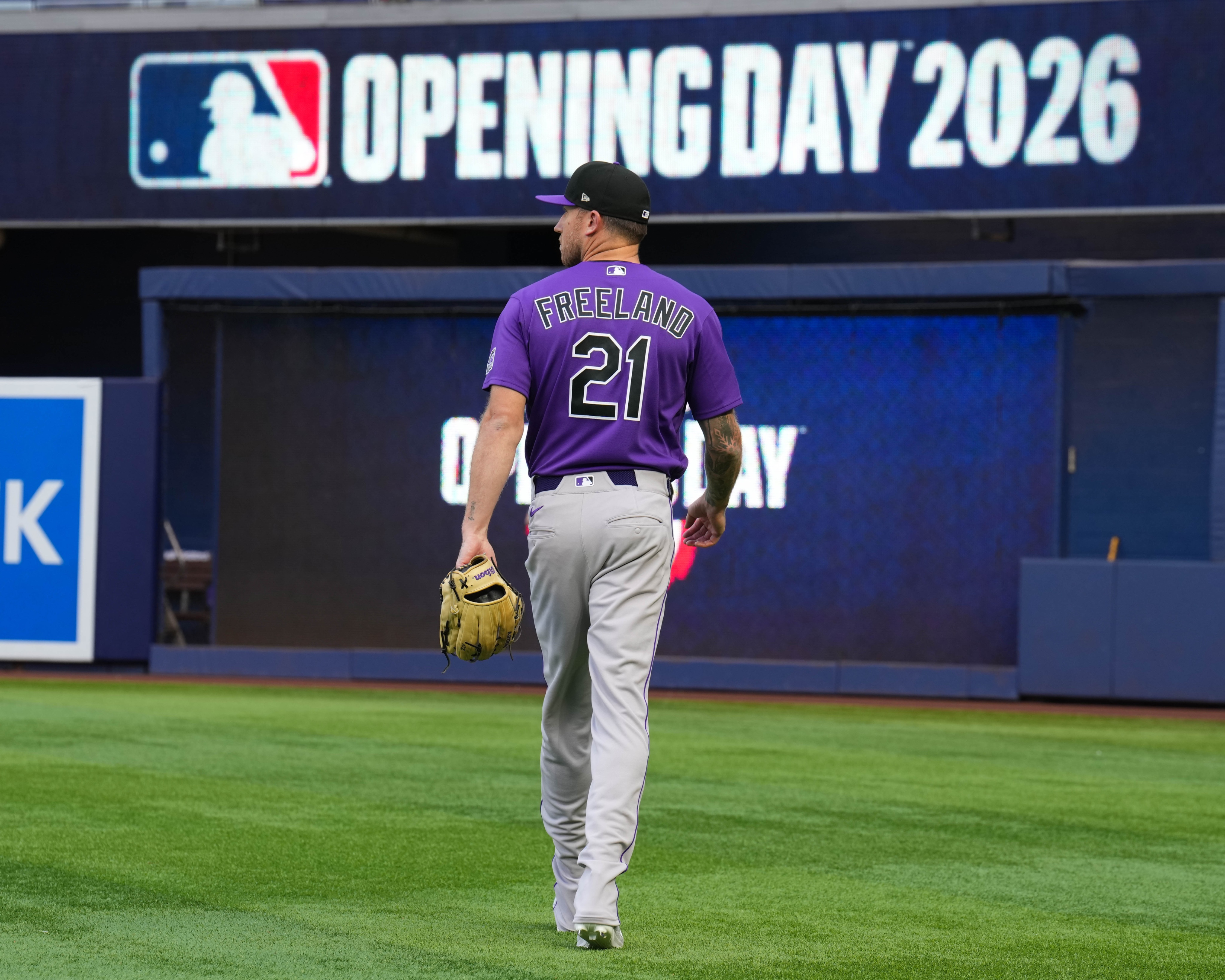 Kyle Freeland walks on the grass at loanDepot park. An OPENING DAY 2026 banner is above his head.