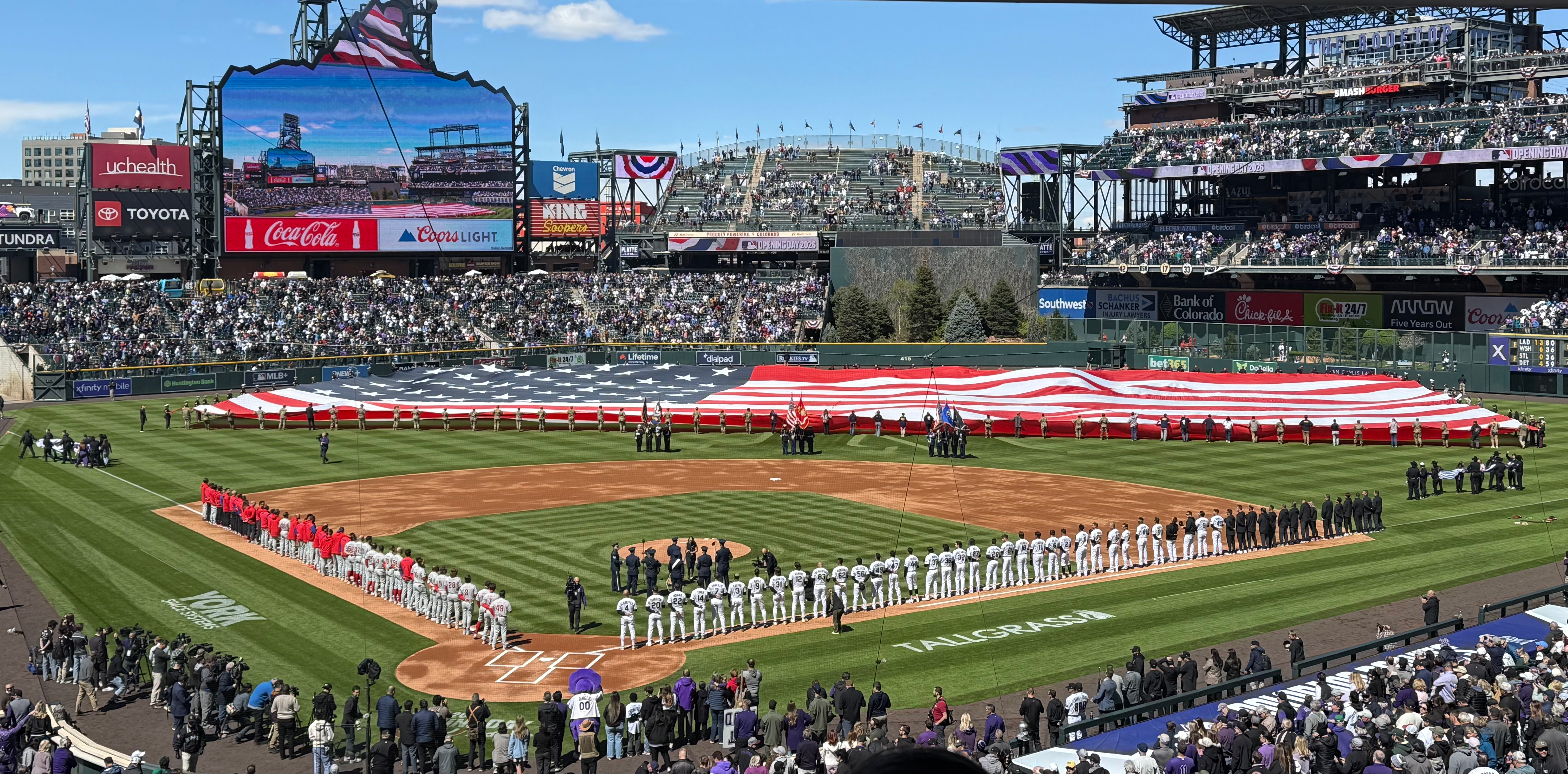 A photo of Coors Field before the game begins. A huge American Flag covers the outfield. 