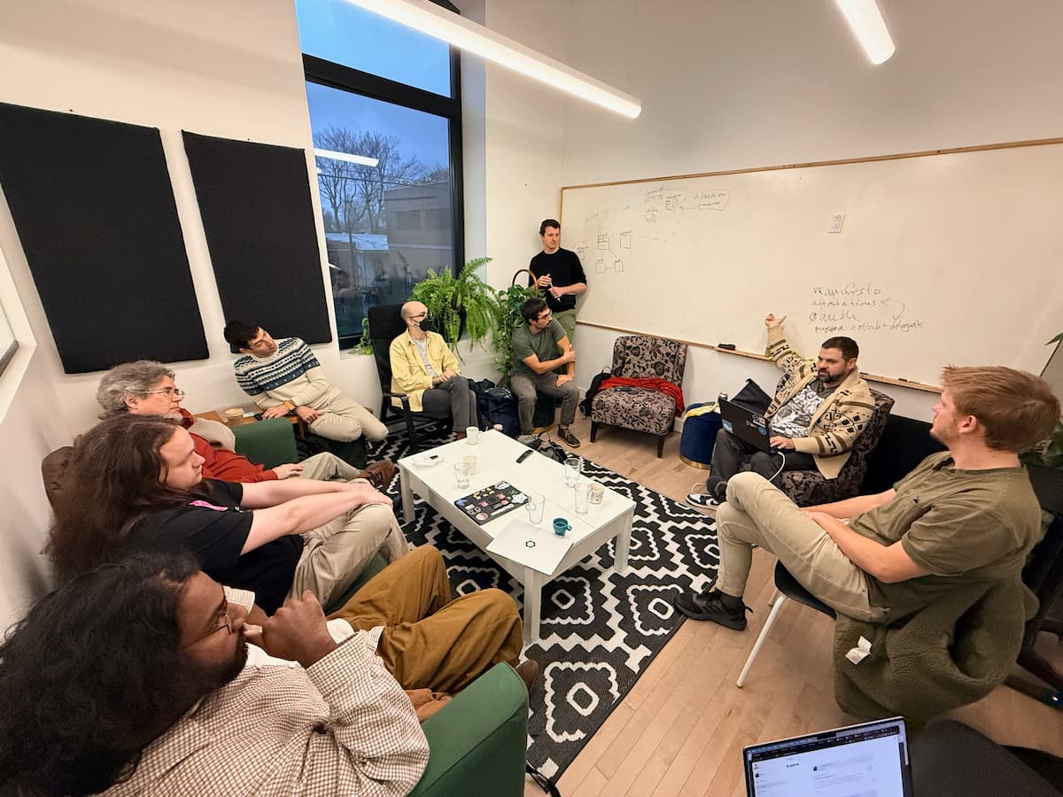 Fisheye of a meeting room with people sitting around the outside. A large whiteboard is on one wall.