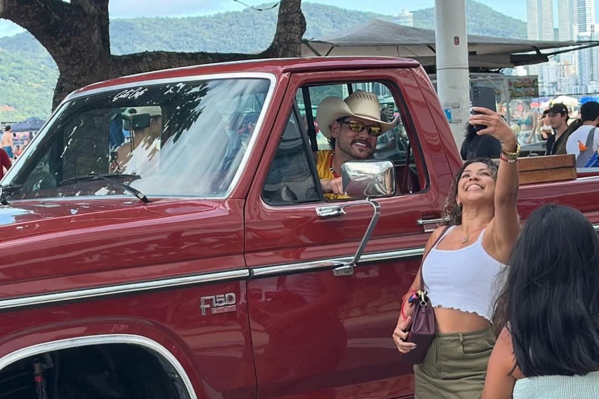 Celebridade sertaneja dentro de um carro enorme com uma pessoa aleatória tirando uma selfie com ele