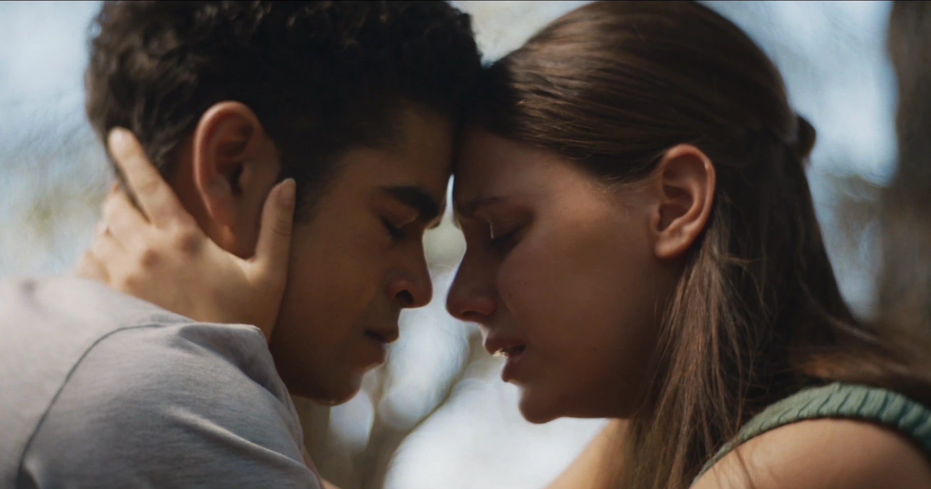 Scène où Lyra et Will tentent de se dire adieu.
A gauche, Will, interprété par Amir Wilson, adolescent noir d'une quinzaine d'années, cheveux noirs, portant un haut gris clair, à droite, Lyra, interprétée par Dafne Keen, adolescente blanche d'une quinzaine d'années, cheveux foncés coiffés vers l'arrière, portant un haut vert, tenant la tête du garçon entre se mains. Toustes les deux ferment les yeux et ont des larmes qui coulent sur leurs visages.
On distingue en arrière-plan, des formes d'arbres, ainsi qu'un ciel bleu.