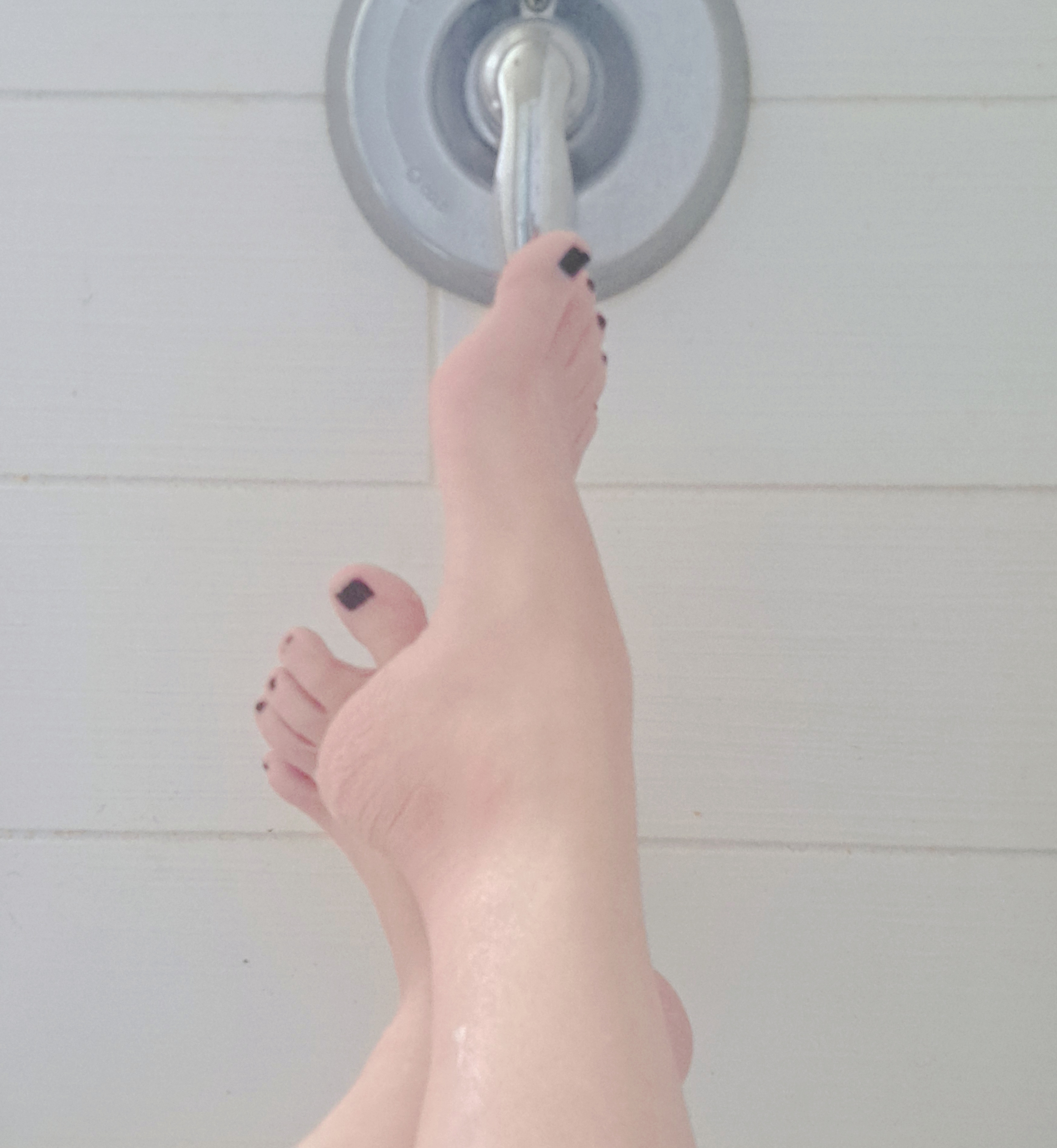Valerie Rayne rests her foot on the faucet and tap in the bath, showing off her tiny black painted toenails and her amazing arch.