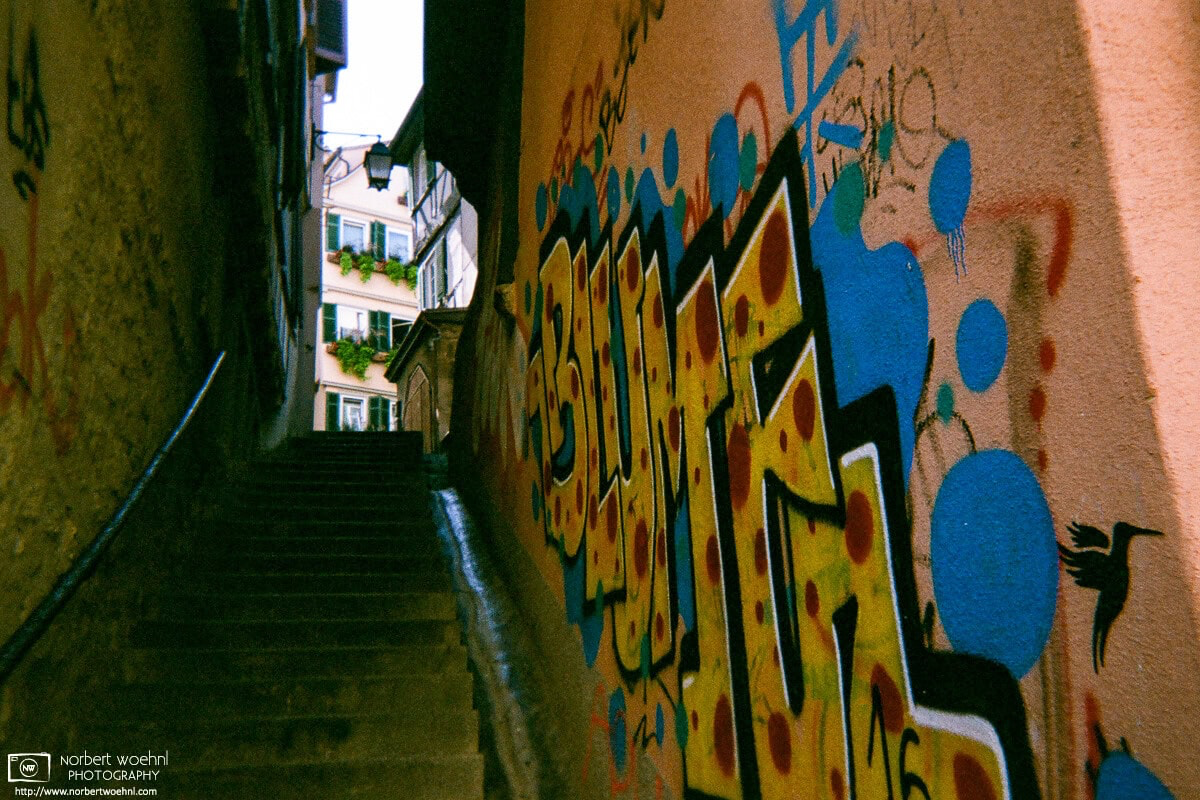 In the historic city center of Tübingen, Germany, some old buildings adjacent to a narrow and steep flight of stairs have been painted with graffiti. © 2018 Norbert Woehnl Photography.