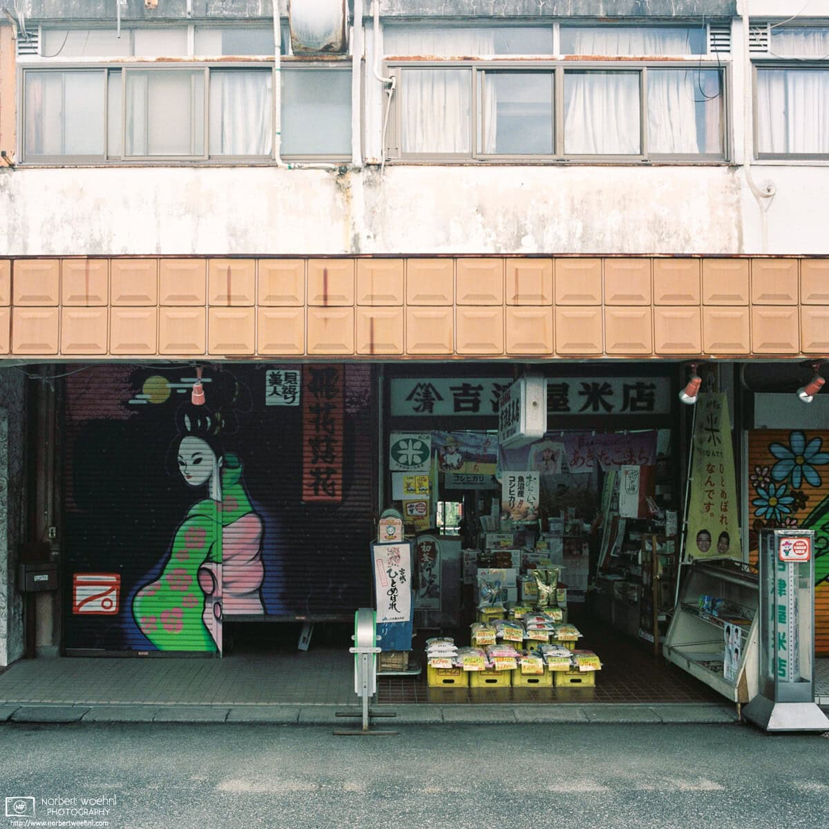 Adjacent to a shutter painted with a colorful Japanese-style figure, a rice store is open for customers at Kirigaoka Shopping Street in Tokyo, Japan. © 2021 Norbert Woehnl Photography.