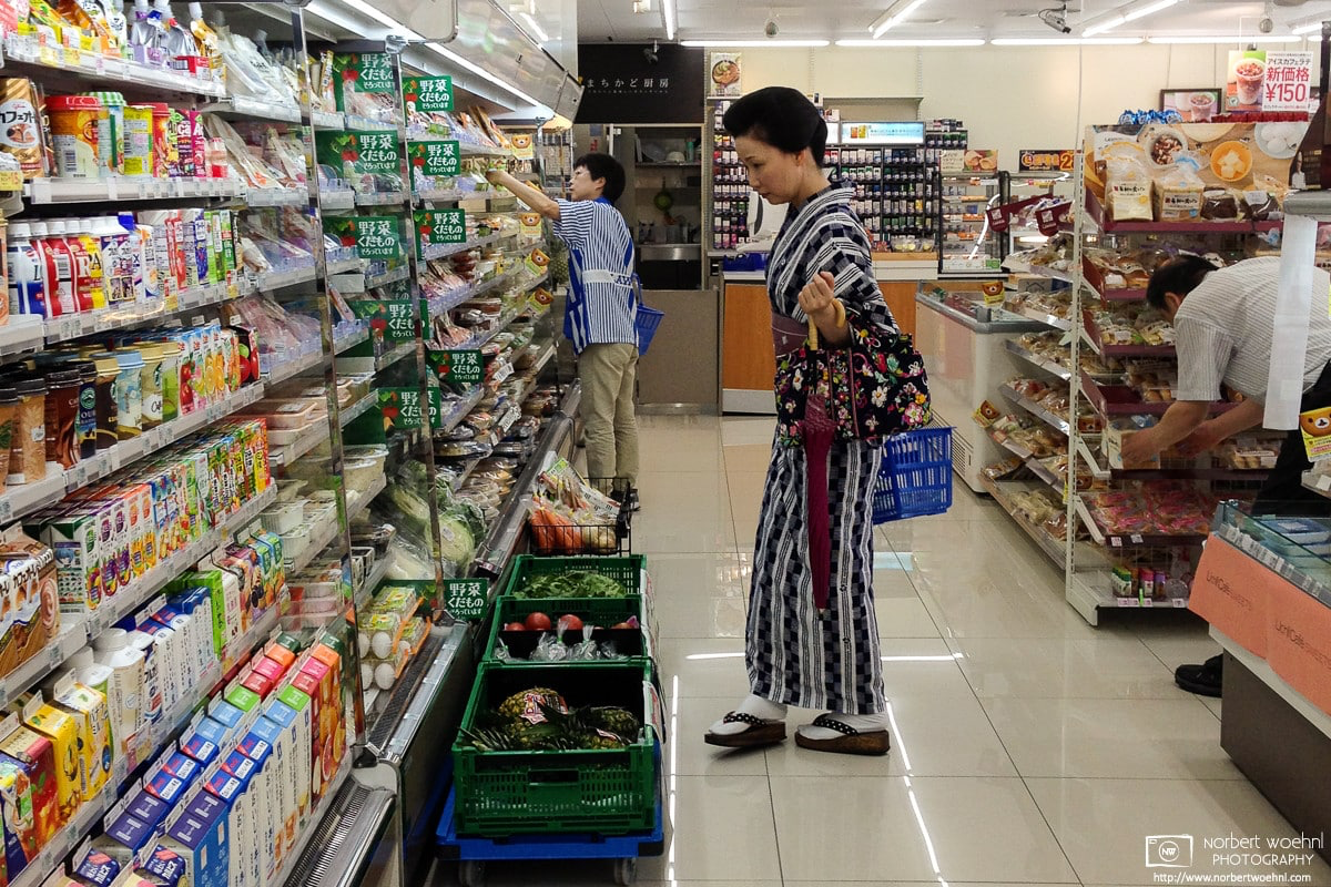 A woman wearing a kimono and geta (Japanese sandals) is shopping at a convenience store in Kanazawa, Japan.  © 2015 Norbert Woehnl Photography.