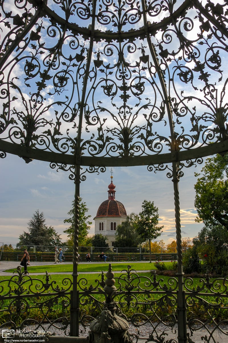 The Bell Tower (Glockenturm) on Schlossberg hill in Graz, Austria, seen through wrought-iron adornments on an adjacent well. © 2006 Norbert Woehnl Photography.