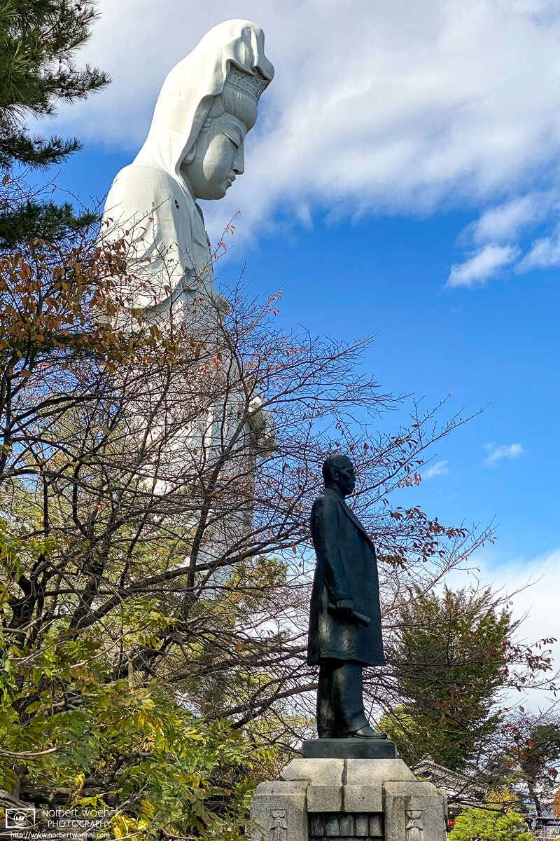 The black statue in the foreground commemorates Inoue Yasusaburo, the local businessman who erected the Kannon statue in 1936. © 2023 Norbert Woehnl Photography.