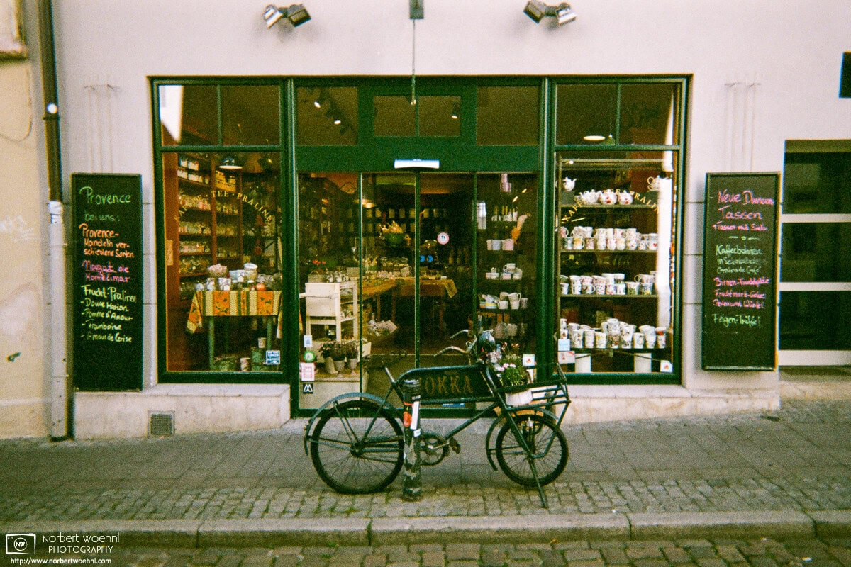 Outside a housewares store in Tübingen, Germany, a dark green bicycle is matching the color scheme of the shops window and door paint. © 2018 Norbert Woehnl Photography.