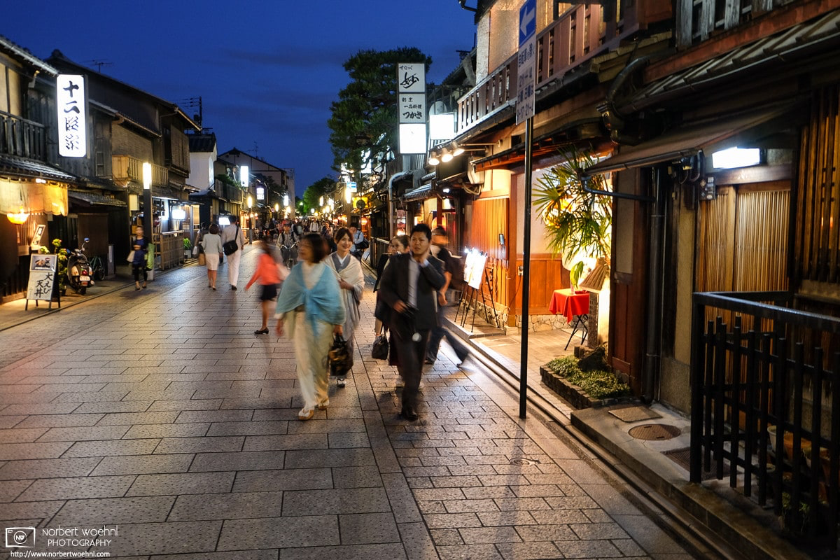In the early evening, people are strolling on Hanamikoji, a main street in the Gion district of Kyoto, Japan. © 2014 Norbert Woehnl Photography.