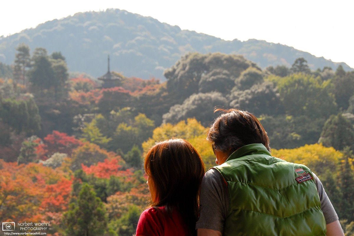 Visitors to Kiyomizu-dera in Kyoto, Japan, are enjoying a view of the autumn-colored natural scenery surrounding the famous temple. © 2006 Norbert Woehnl Photography.