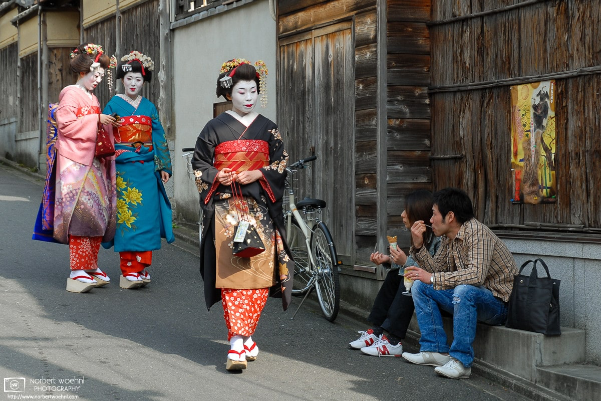 At Ninenzaka in Kyoto, Japan, a young couple in casual clothes is watching three women in Maiko attire. © 2006 Norbert Woehnl Photography.