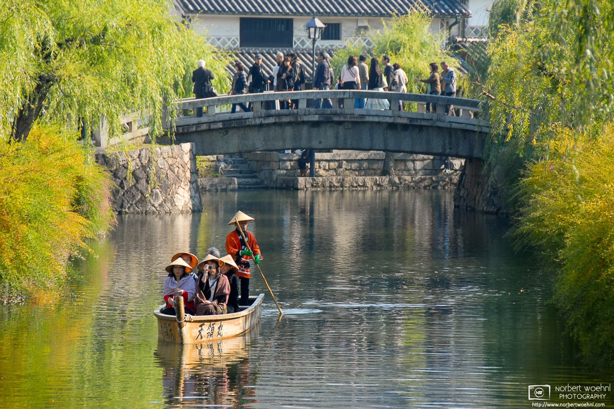 During early autumn season, visitors are enjoying a boat ride on a willow-lined canal in the historic Bikan district of Kurashiki in Okayama Prefecture, Japan. © 2009 Norbert Woehnl Photography.