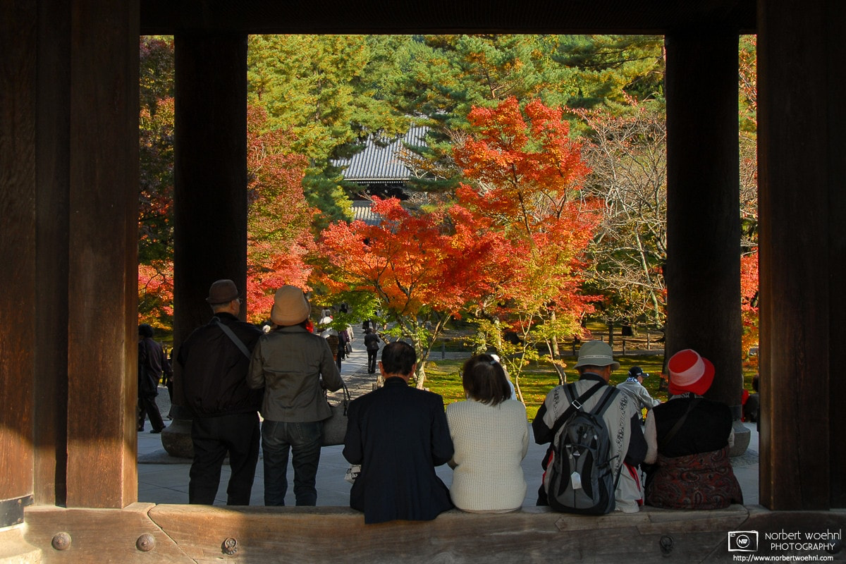 At Nanzenji Temple in Kyoto, Japan, visitors are seen enjoying autumn colors while seated in the door frame of the Sanmon Gate. © 2006 Norbert Woehnl Photography.