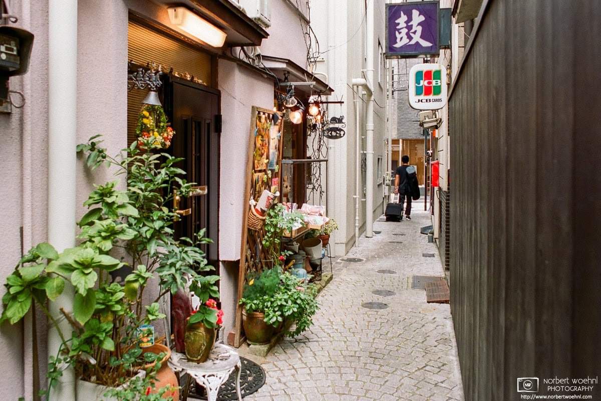 In the Kagurazaka area near Iidabashi Station in Tokyo, Japan, this is a view into a colorful narrow alley with an inviting-looking shop entrance. © 2018 Norbert Woehnl Photography.