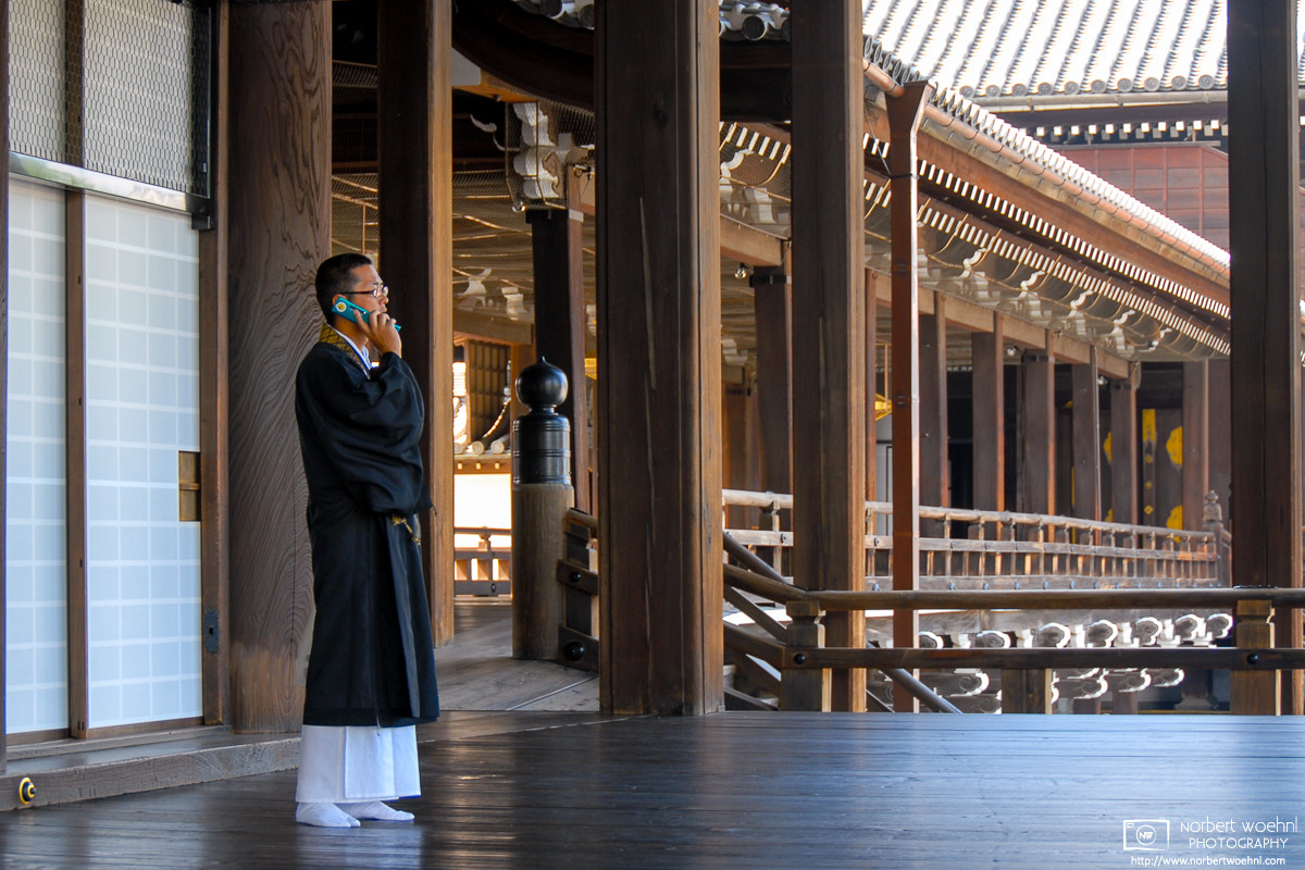 A priest is speaking on a mobile phone at Nishi-Honganji Temple in Kyoto, Japan. © 2010 Norbert Woehnl Photography.