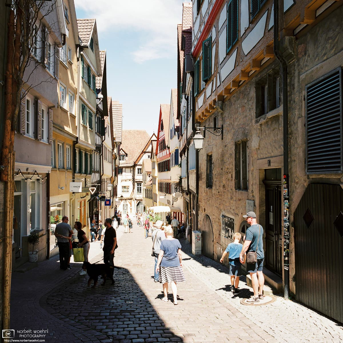 People are walking along Marktgasse, a cobblestone street between half-timbered buildings in the historic city center of Tübingen, Germany. © 2017 Norbert Woehnl Photography.