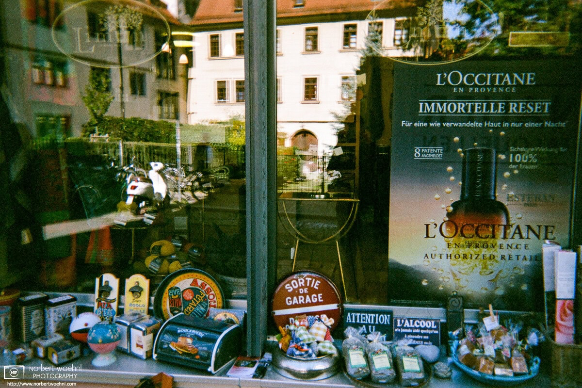 A shop window in Tübingen, Germany, reflects the scenery of historic buildings around the store. © 2018 Norbert Woehnl Photography.