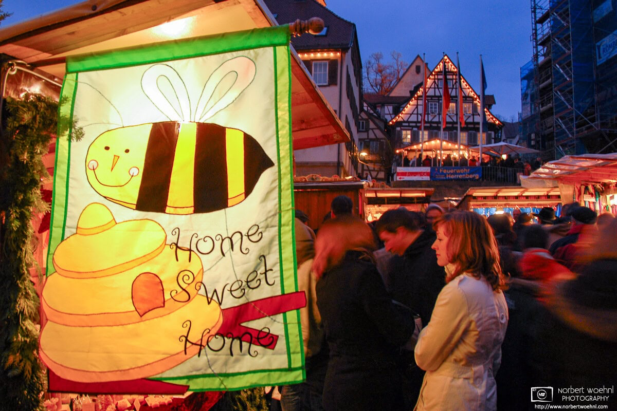 At the Christmas Market in the historic town of Herrenberg in southwestern Germany, people are looking at a stand selling honey and beeswax products. © 2008 Norbert Woehnl Photography.