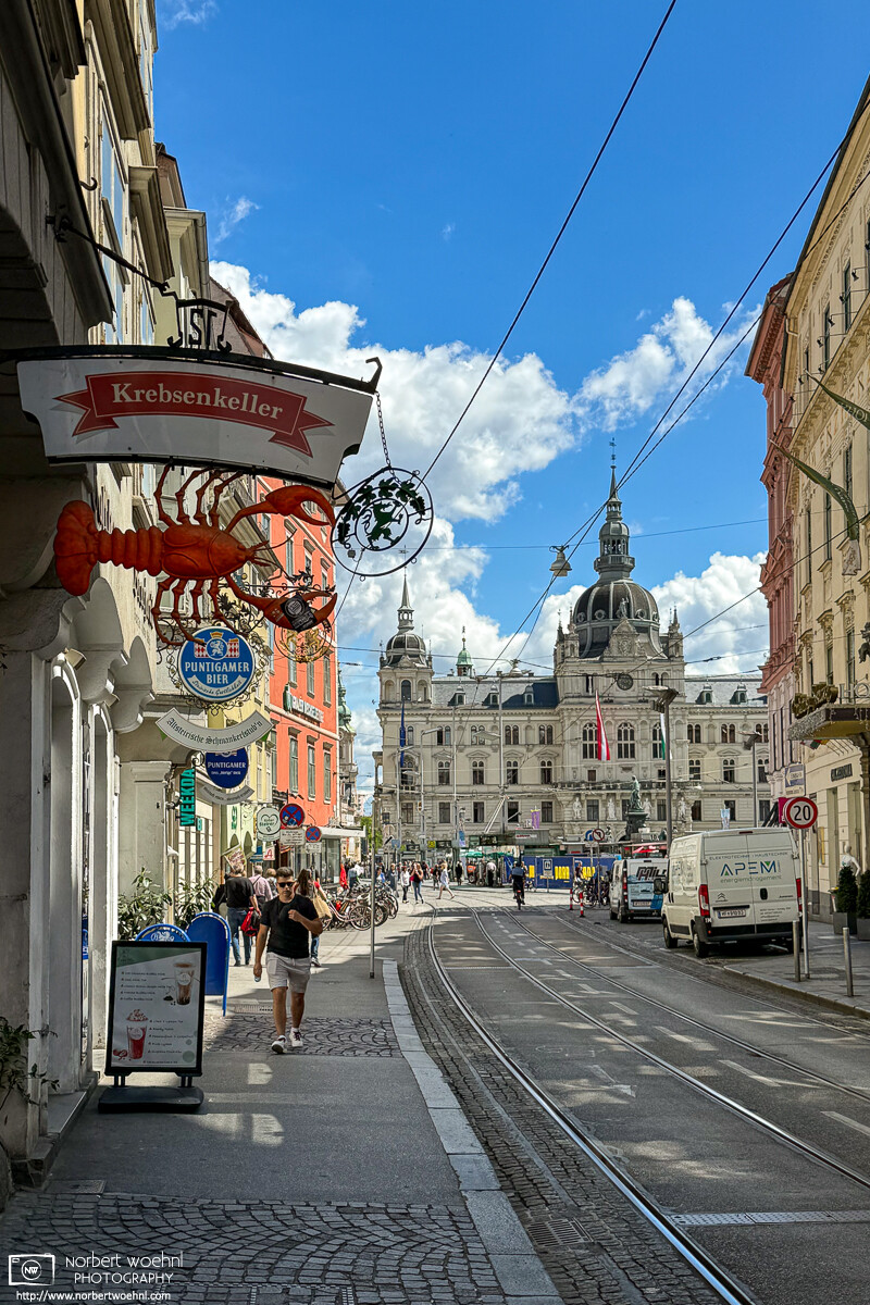 At Sackstraße, a narrow street in the historic city center of Graz, Austria, tram tracks are leading the perspective towards the City Hall building that is visible in the background. © 2024 Norbert Woehnl Photography.