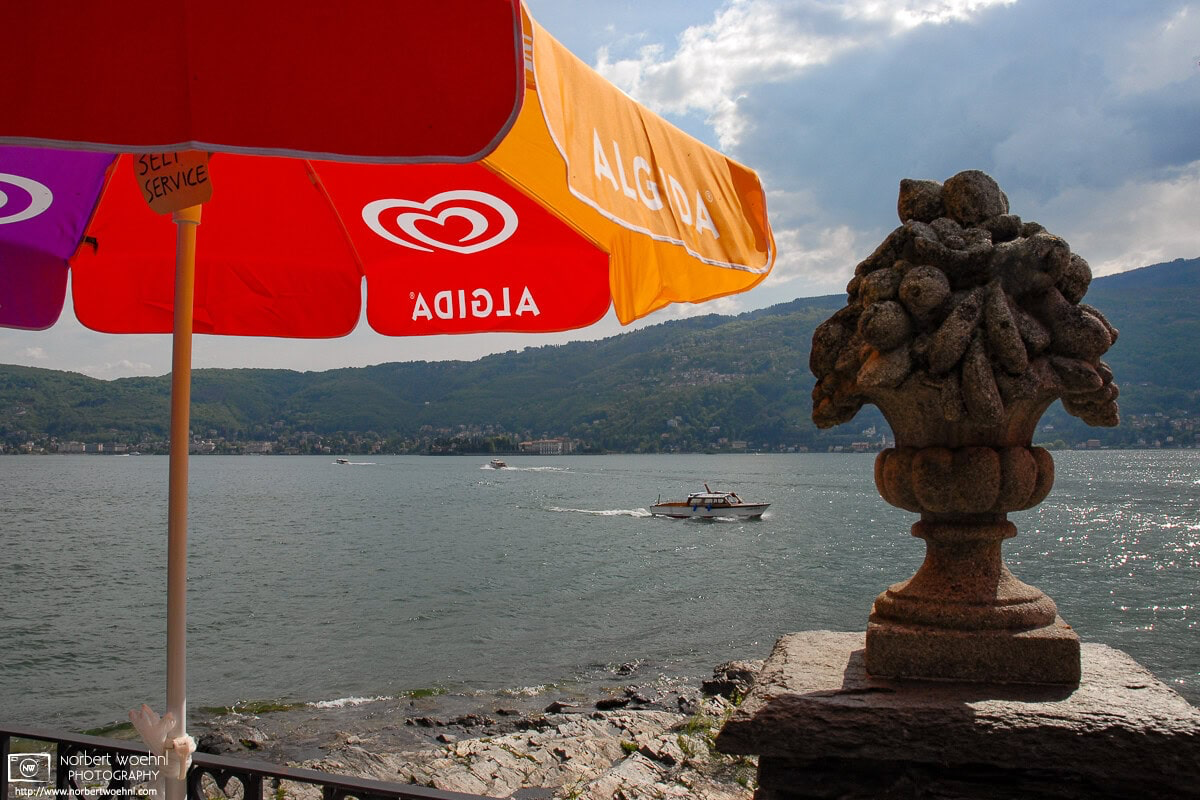 View from underneath a parasol on Isola Madre towards some light boat traffic on Lago Maggiore, Italy. © 2006 Norbert Woehnl Photography.