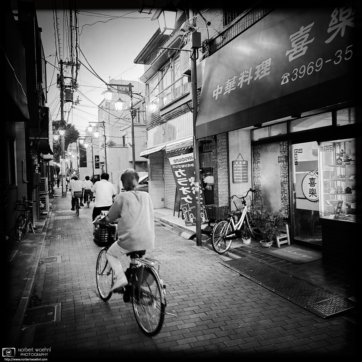 Monochrome evening scene from Inari-dori Shopping Street in the Miyamotocho area of Itabashi Ward in Tokyo, Japan. © 2025 Norbert Woehnl Photography.