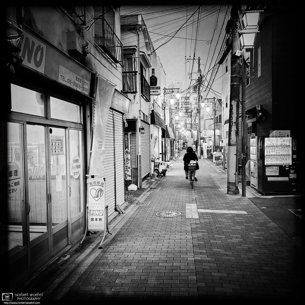 Monochrome evening scene from Inari-dori Shopping Street in the Miyamotocho area of Itabashi Ward in Tokyo, Japan. © 2025 Norbert Woehnl Photography.