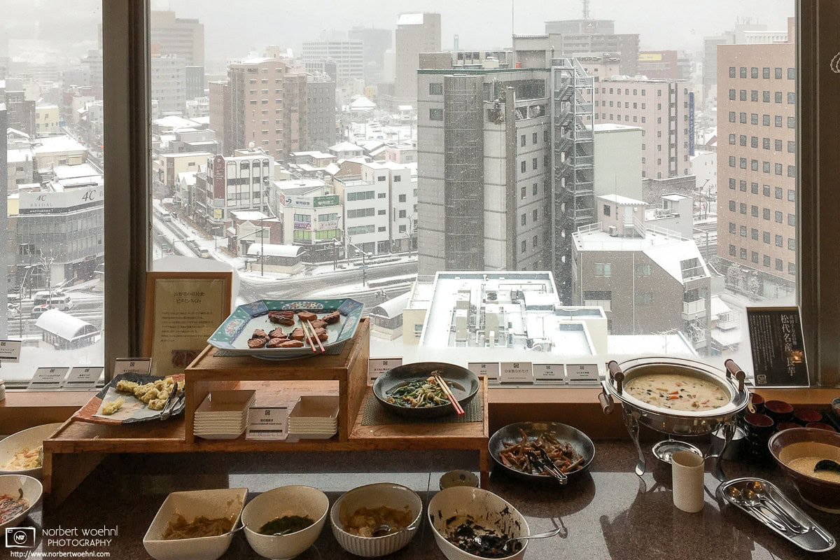 Part of a hotel breakfast buffet in Nagano, Japan, with an outside view of the city scenery on a snowy day. © 2017 Norbert Woehnl Photography.