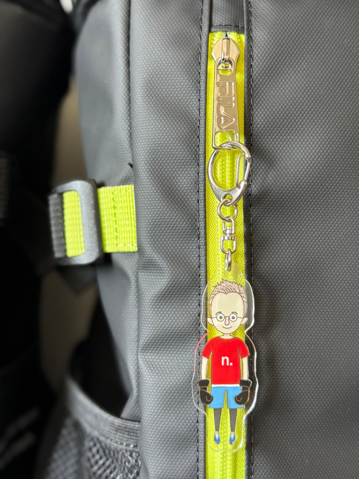 Detail of key ring with illustration of a male character in kickboxing sports gear, attached to a sports bag. © 2025 Norbert Woehnl Photography.