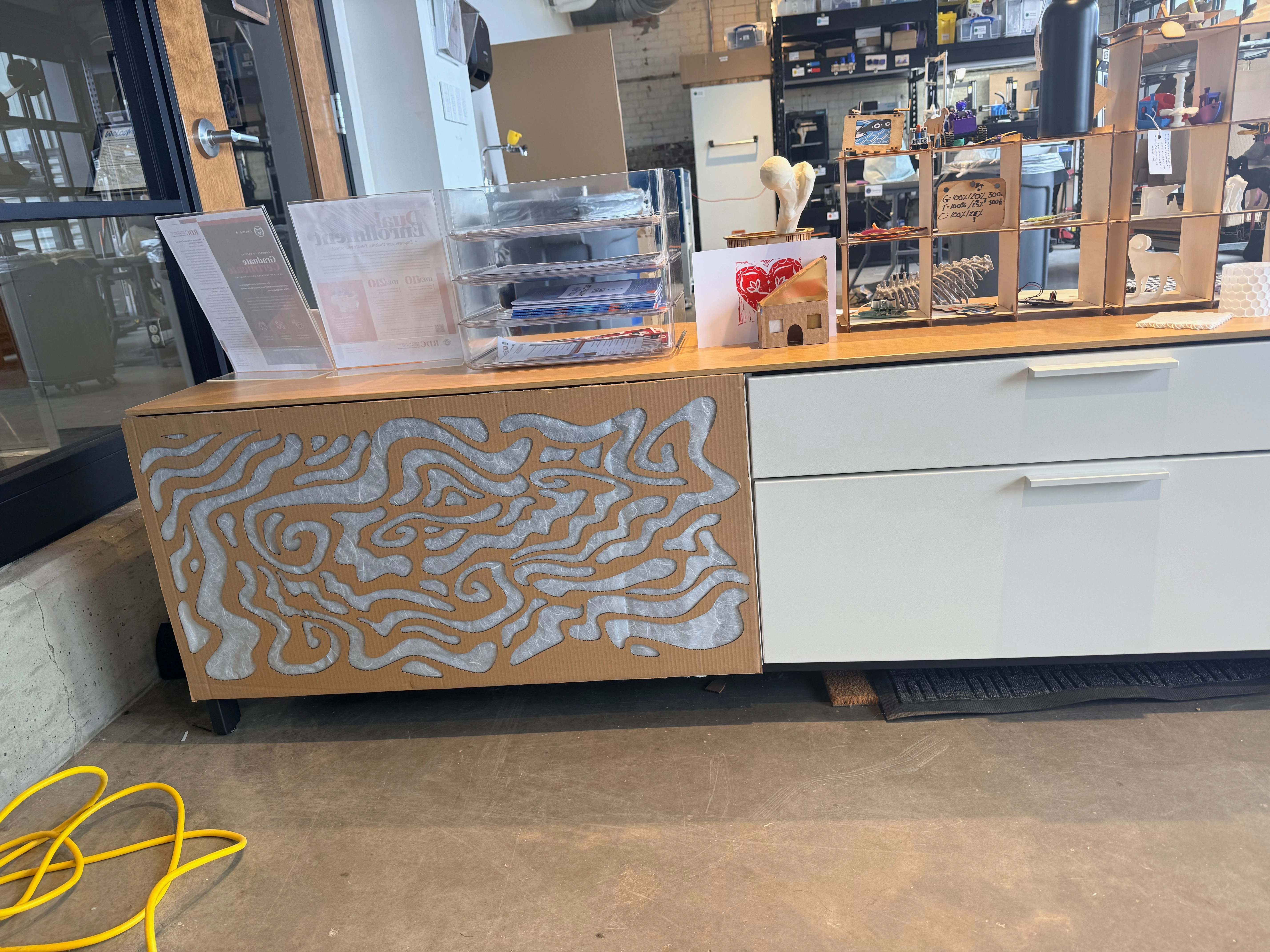 the same file cabinet from the previous image. Now, the open side of the cabinet is complete covered by a decorative cardboard cut-out with slightly translucent decorative paper visible behind the spots in the cardboard that are cut out. 