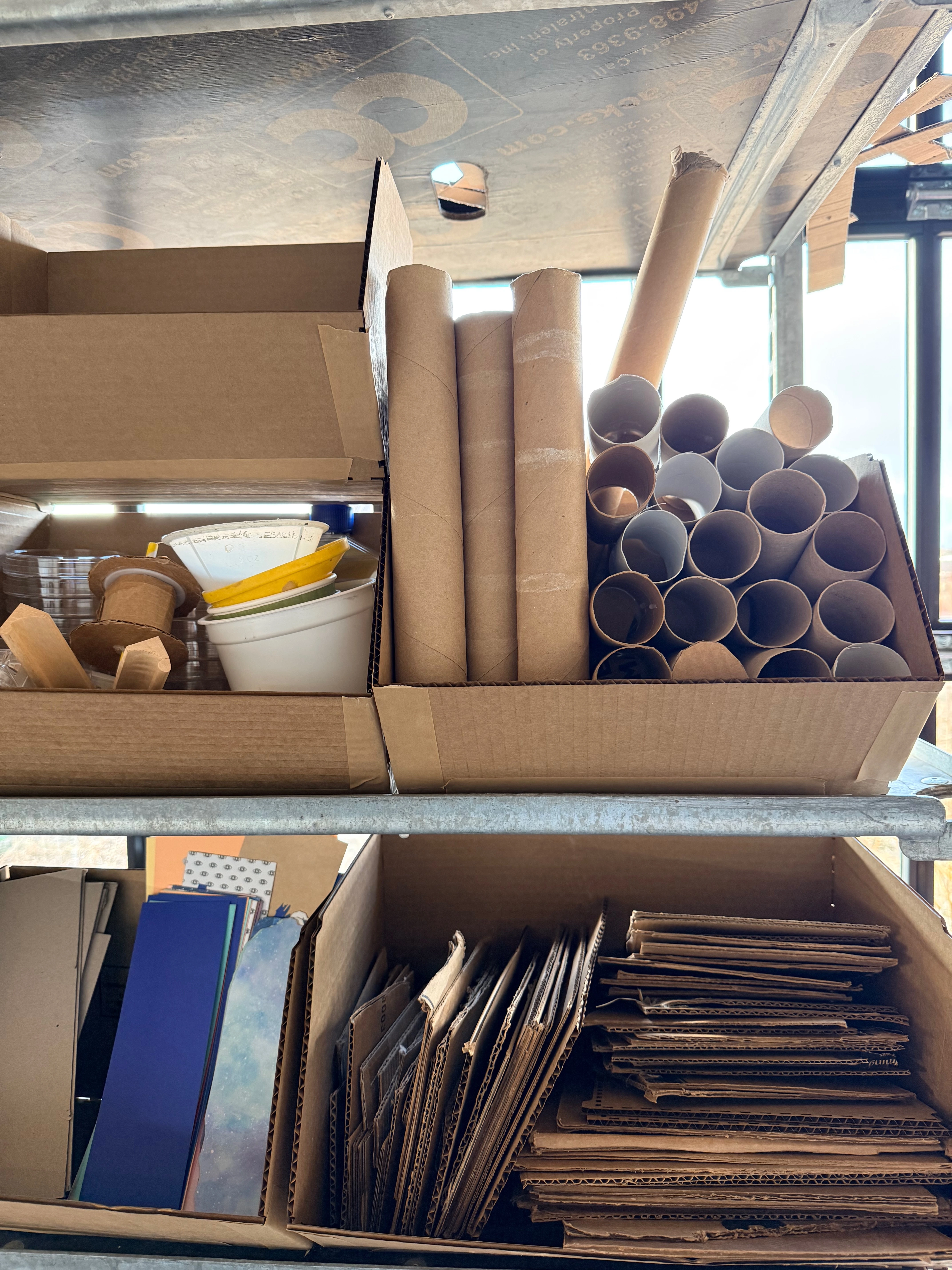 A close up view of some of the bins on the cart which hold cardboard rolls, small cardboard sheets.